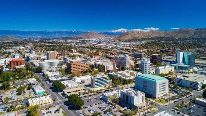 Downtown Riverside skyline aerial view with Blue Mountain (center), Box Springs Mountain (right), and the partially snowcapped San Bernardino Mountains in the far distance.