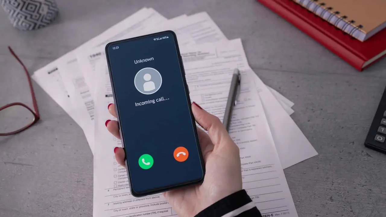 Person holding mobile and smartphone in office.