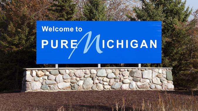 Blue welcome to pure michigan sign on a stone wall stock photo