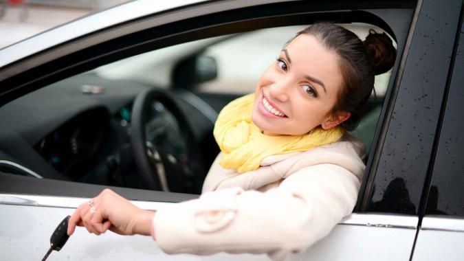 Woman buying car Happy smiling woman showing key from her new car.