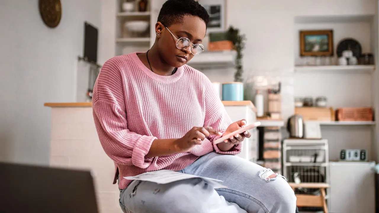 Picture of a young woman sitting down and going over her finances in her home in the morning