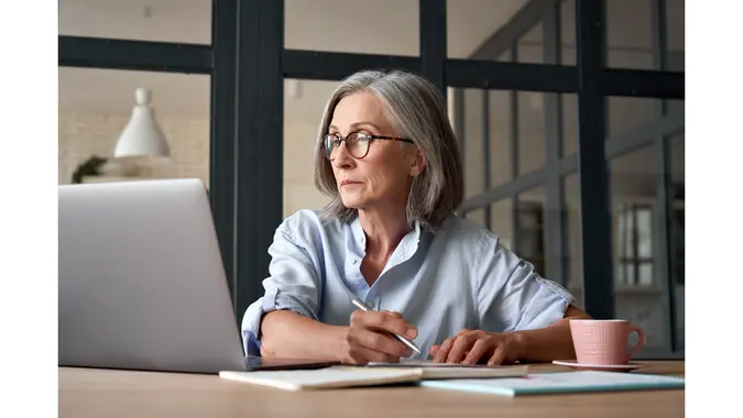A woman sits in front of her laptop and does her work.
