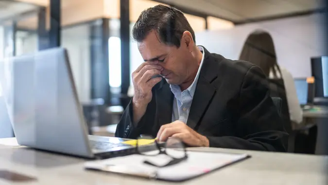 Worried mature businessman working using a laptop at office stock photo