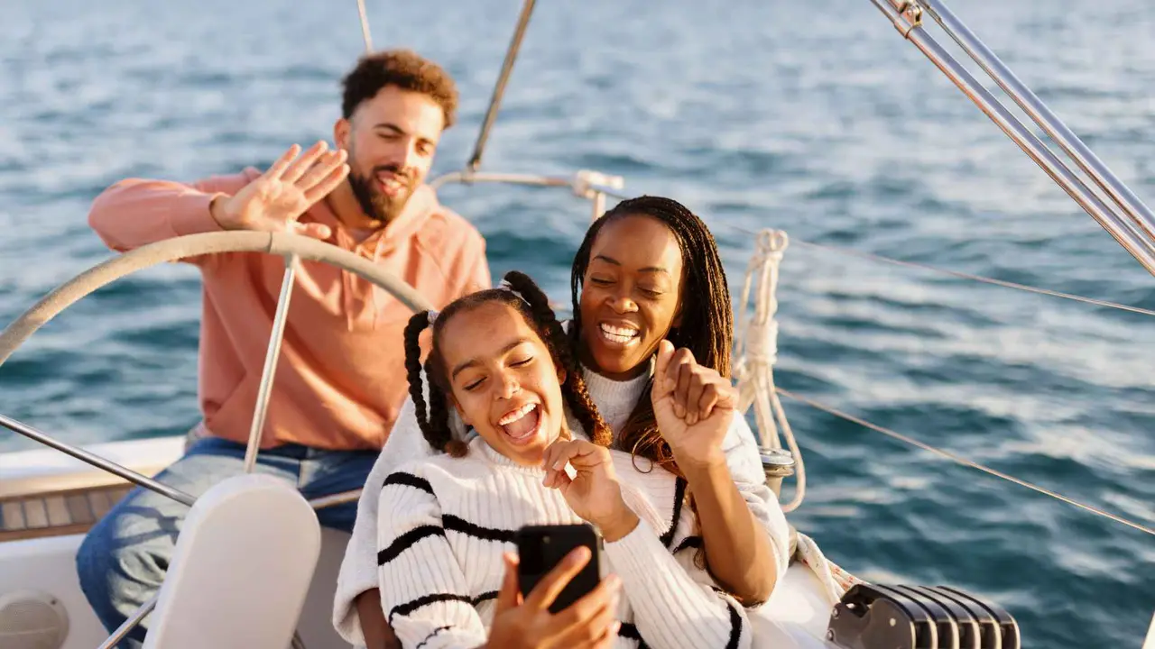 A family smiles while taking a trip on their yacht.