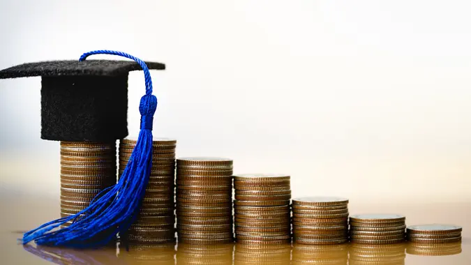 Graduation hat on coins money on white background. stock photo