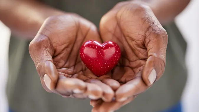 Close up of african woman hands holding red heart in solidarity stock photo