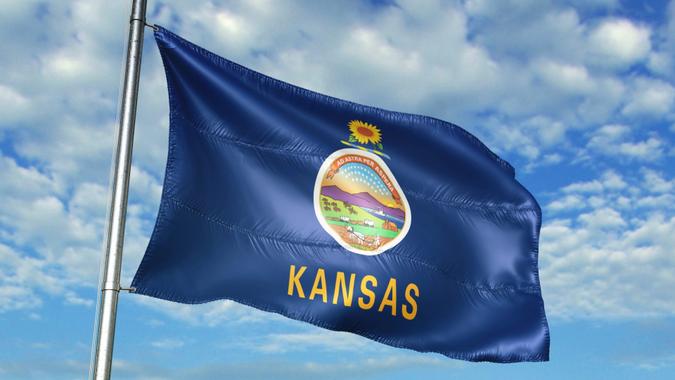 Kansas state of United States flag on flagpole waving cloudy sky background realistic 3d illustration.