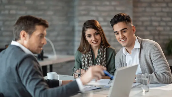 Young smiling couple and their financial consultant using computer on a meeting in the office.