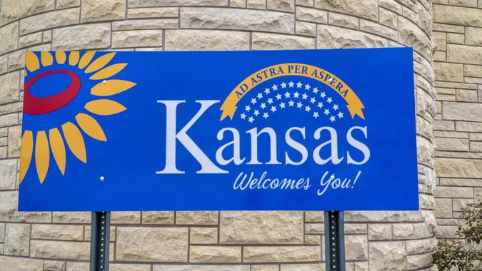 Kansas welcomes you - welcome roadside sign at freeway rest area with a popular Latin phrase ad astra per aspera (through hardships to the stars), driving and travel concept.