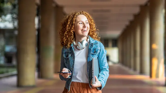 Young woman holding laptop and smart phone.