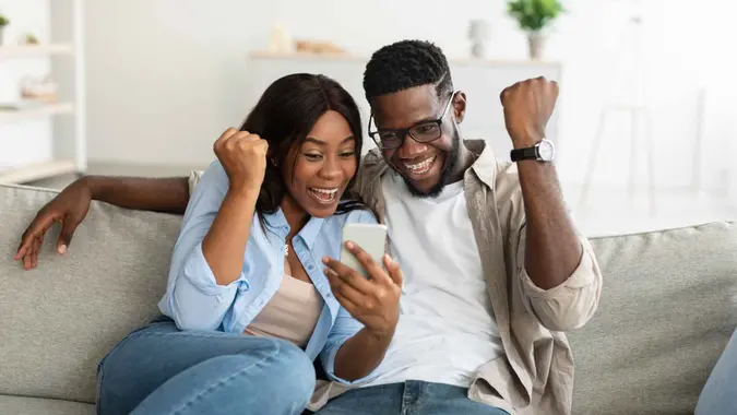 Couple sitting on a couch in the living room and reading great news.