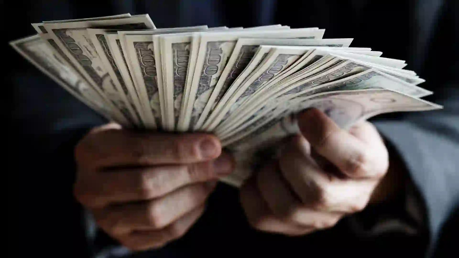 Closeup of hands holding $100 bills.
