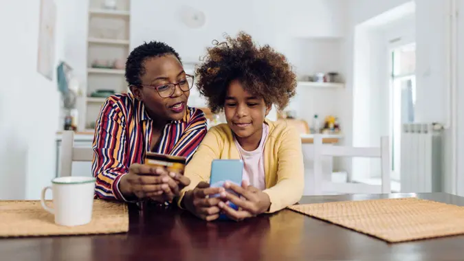 African American teenage girl enjoying at home with grandmother and shopping online.