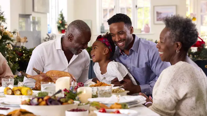 Multi-Generation Family Celebrating Christmas At Home With Grandfather Serving Turkey.