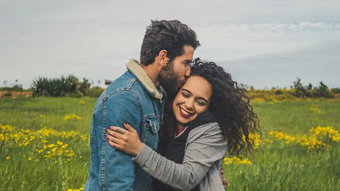 Happy couple hugging and smiling while standing in the grass.