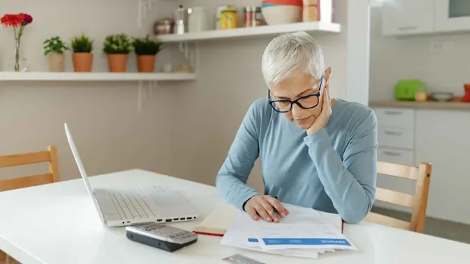 A woman puts her hand on her face while looking at documents.