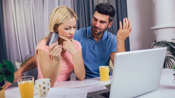 Happy couple at home paying bills with laptop and credit card stock photo