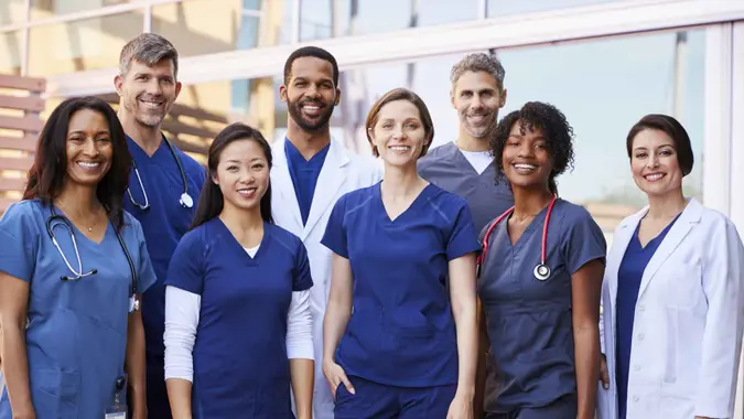 Smiling medical team standing together outside a hospital.