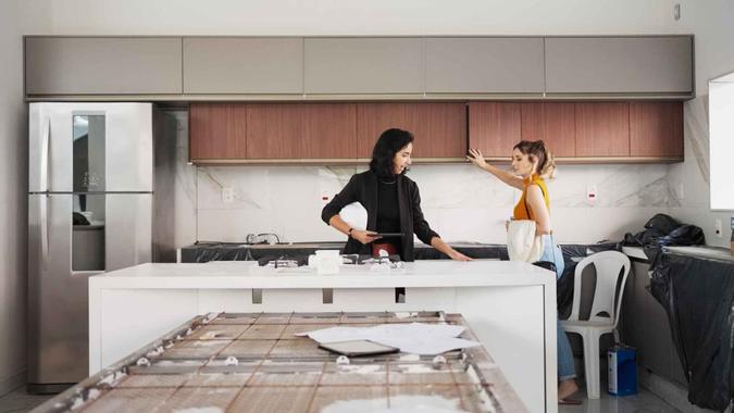 Two women architects inspecting kitchen and discussing the renovation plan at under construction site.