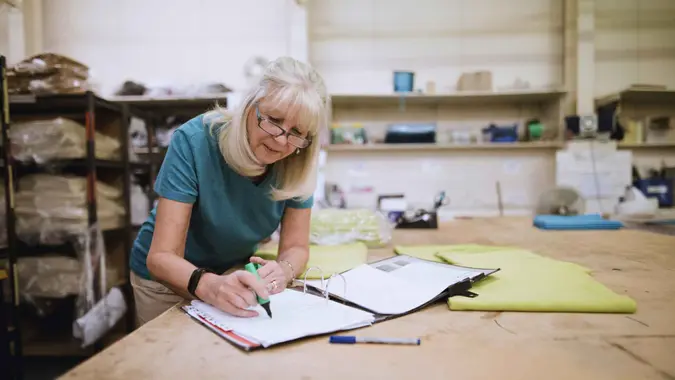 Senior businesswoman is doing paperwork in her stock factory.