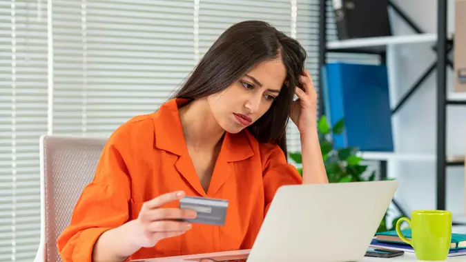 A woman looks worried while making an online credit card purchase.
