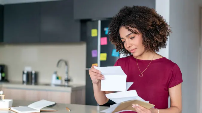 Portrait of an African American woman at home reading a letter in the mail - domestic life concepts.