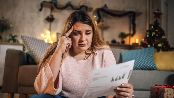 Young worried woman manage finances during Christmas holidays.