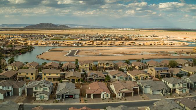 Panoramic aerial shot of Maricopa, Arizona, flying over a growing housing development being built around an artificial lake.