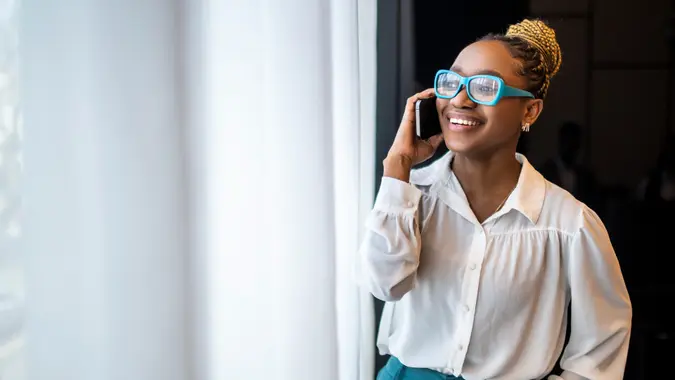 A young woman smiles while talking on the phone.