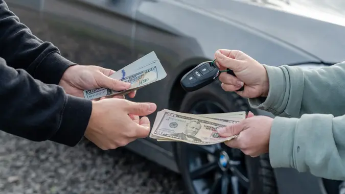 Deal of buying or renting car concept. Hand with car keys, other hand gives money. stock photo