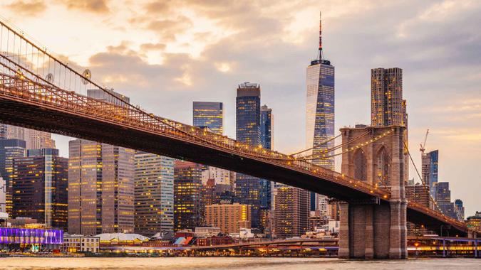 New York City skyline at sunset with Brooklyn Bridge and Lower Manhattan.