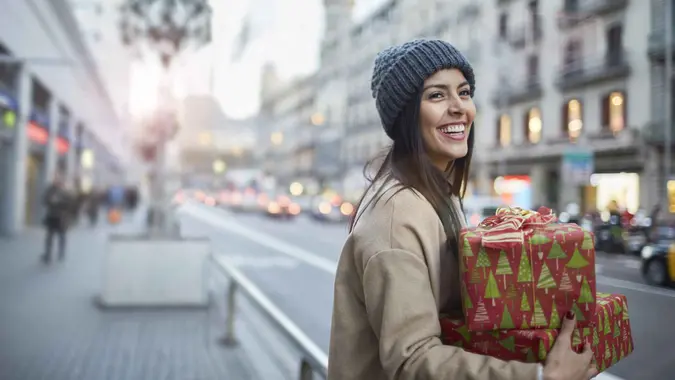 A woman smiles while holding a Christmas gift
