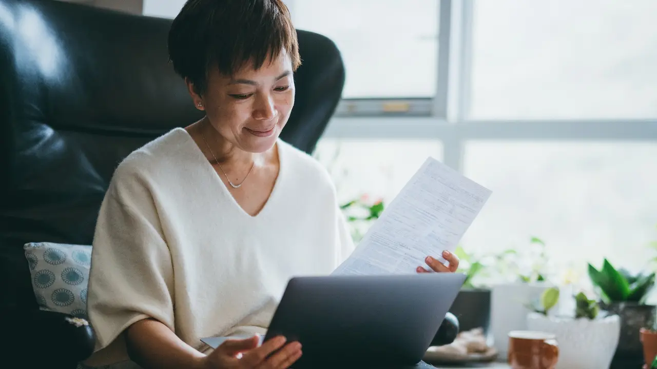 A woman checks her bills while sitting in her home office during her work day.