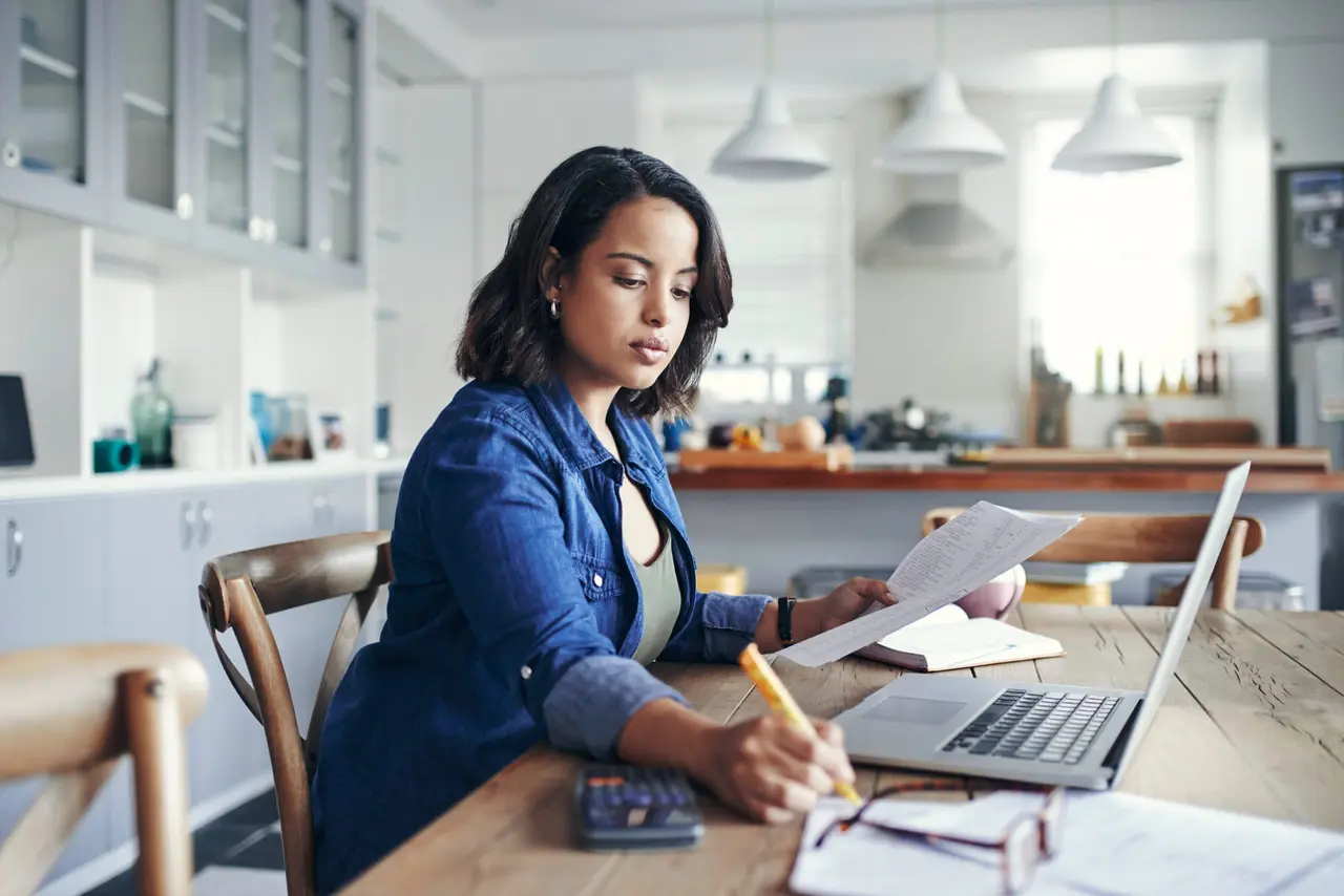 Une femme travaille à son bureau dans sa cuisine à la maison.