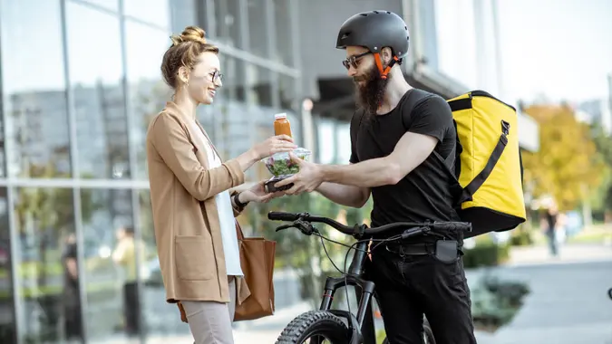 A man works a side gig job as a food delivery person.