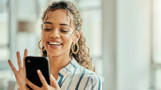 A woman smiles while looking at her phone at work.