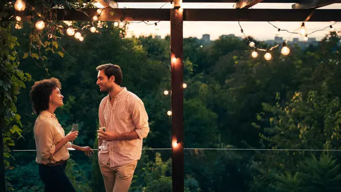 An affectionate young couple standing on a balcony and drinking champagne.