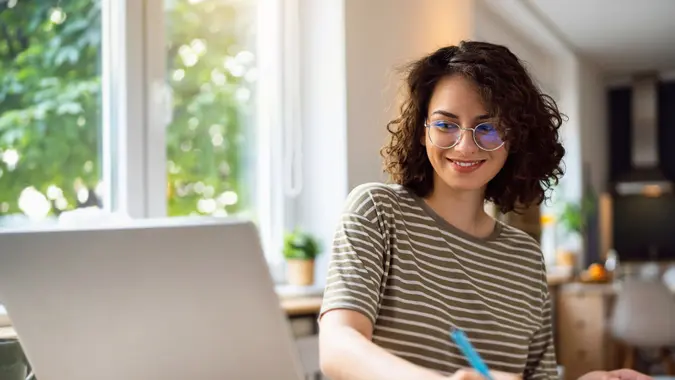 A happy woman smiles and does work at her desk.
