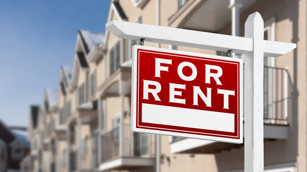 For Rent Real Estate Sign In Front of a Row of Apartment Condominiums Balconies and Garage Doors.