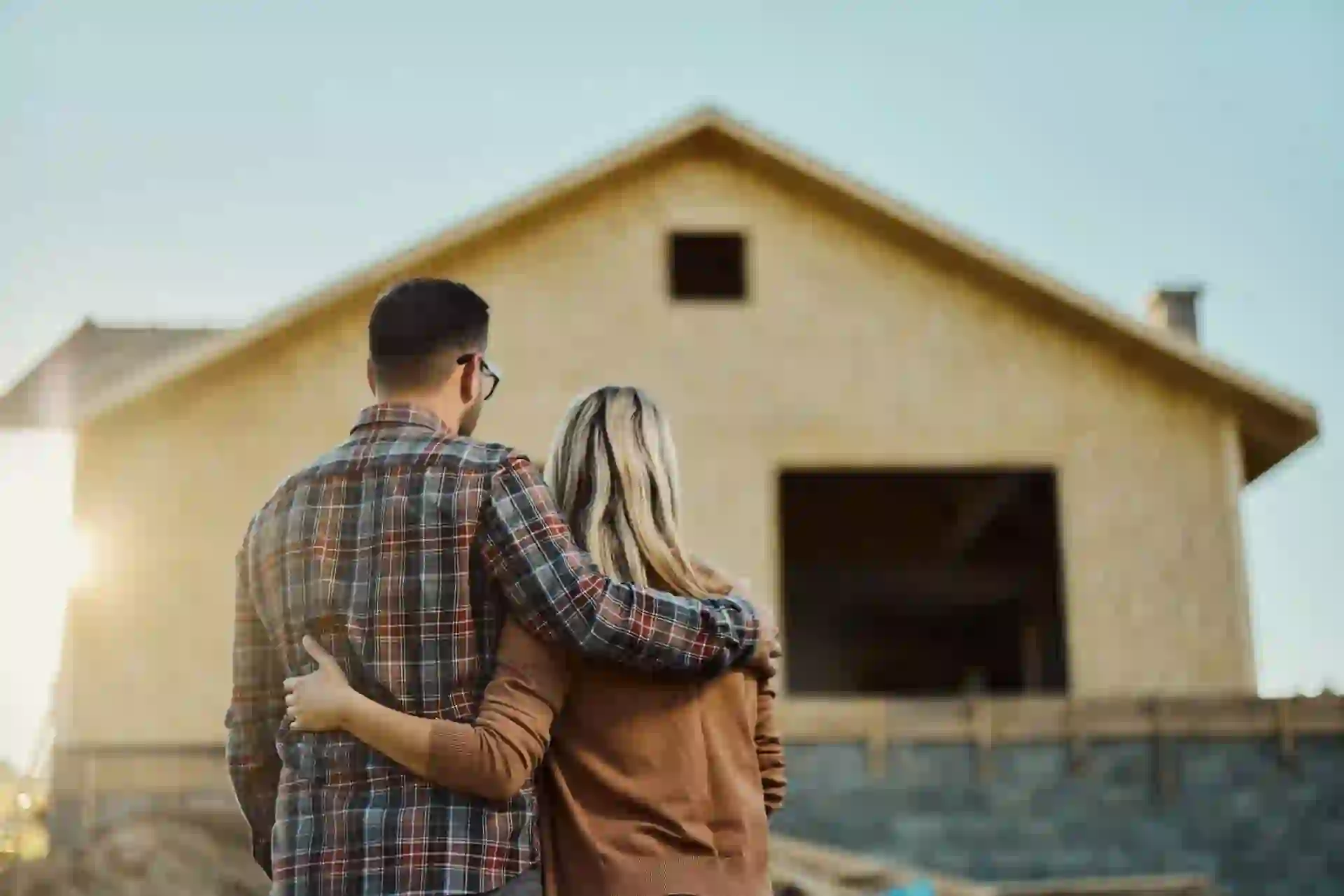 Rear view of an embraced couple looking at built structure from outside.