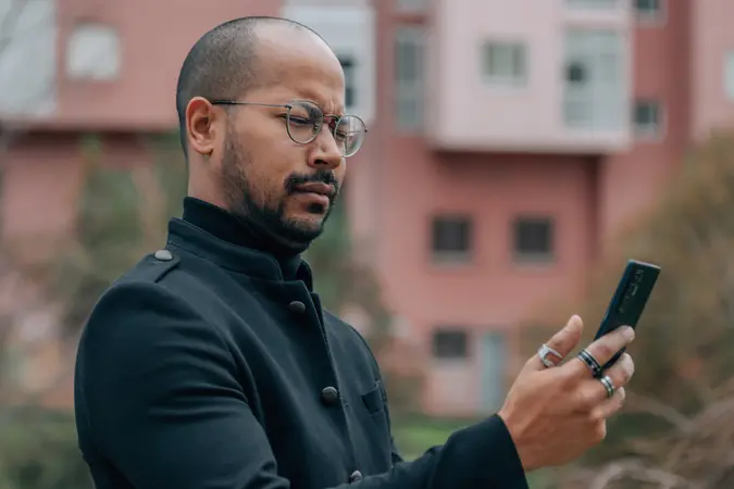 Latino business man in the street looking upset at the mobile phone.