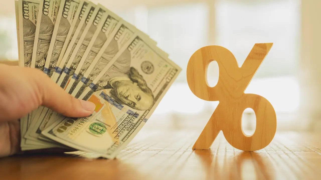 Percent symbol with people holding money that is many dollar bills. Concepts of the banking system, rising interest rates, inflation, deflation, and savings. stock photo