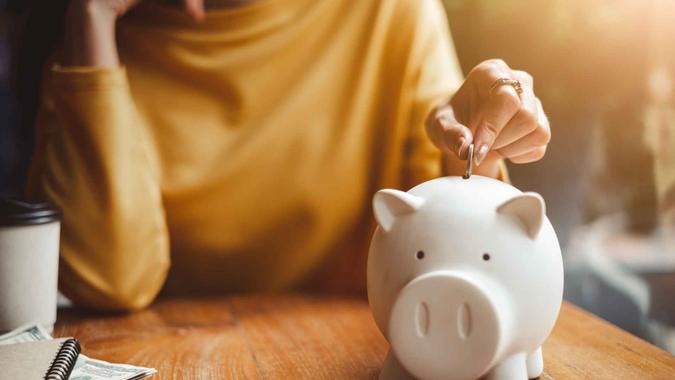 woman hand putting money coin into piggy for saving money wealth and financial concept.