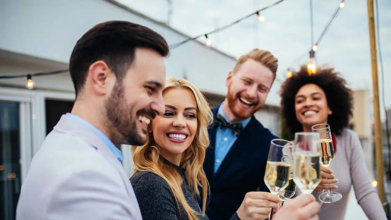 A group of wealthy friends are smiling, drinking champagne and enjoying the rich life.