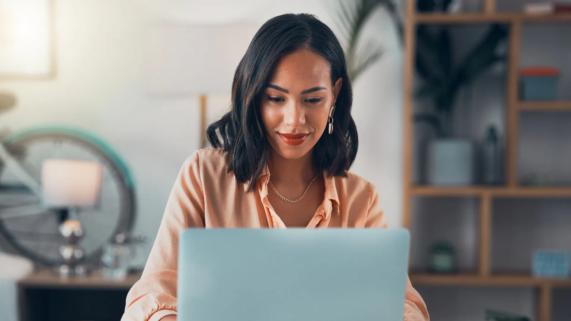 A woman looks happy while checking her messages on her laptop at work.