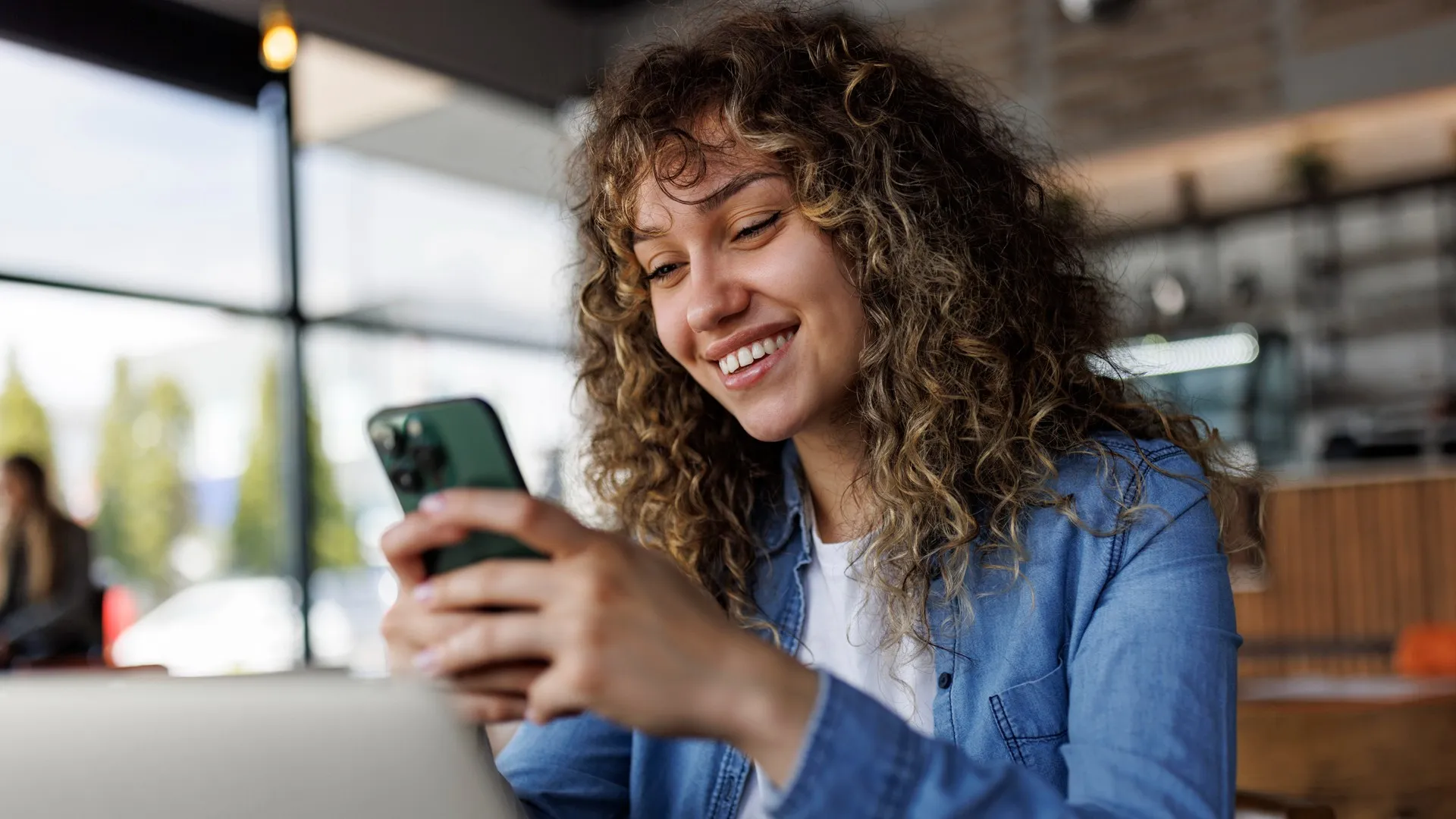 A woman smiles as she checks her phone.