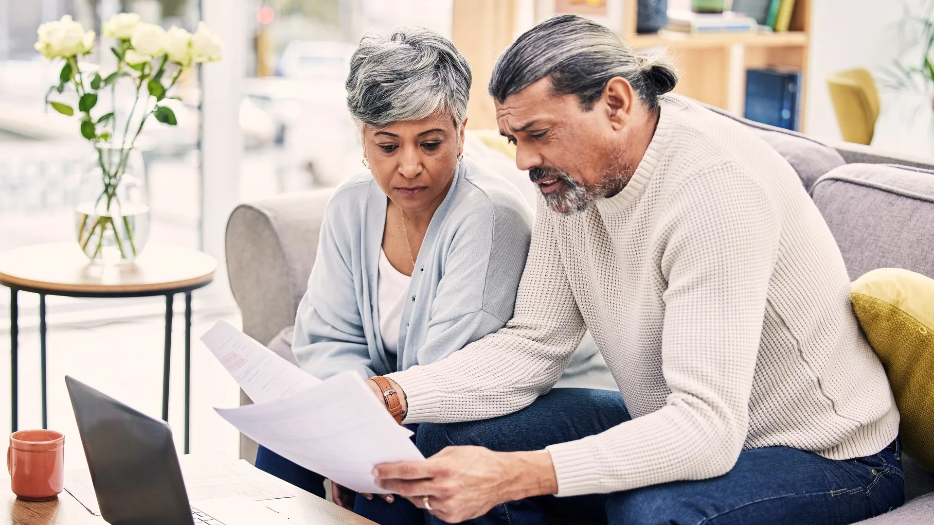 A retired couple sits in their living room and goes over financial paperwork.