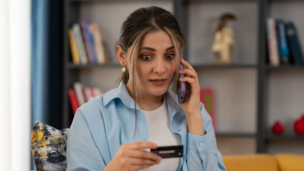 A woman looks shocked as she stares at her credit card.