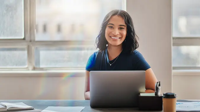 A woman smiles while at her desk at work.