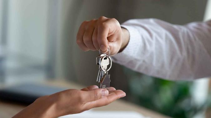 Close up professional Real estate agent giving keys to client, congratulating with purchasing own dwelling after signing contract agreement, professional real estate services, last mortgage payment concept.